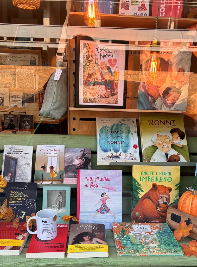 Vetrina di una libreria con libri e illustrazioni dedicati ai nonni, tra cui 'Festa dei Nonni' e 'Tutti gli attimi di Bea'.