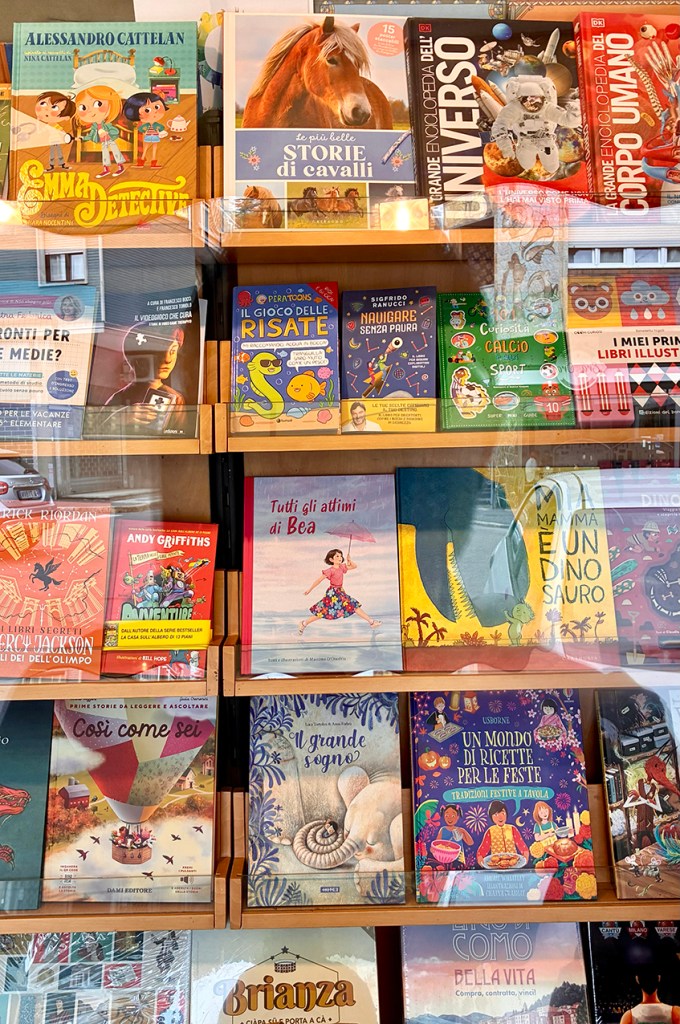 Libreria con una selezione di libri per bambini, inclusi titoli su storie di cavalli, l'universo e ricette per feste. Diversi colori e copertine visibili sugli scaffali.